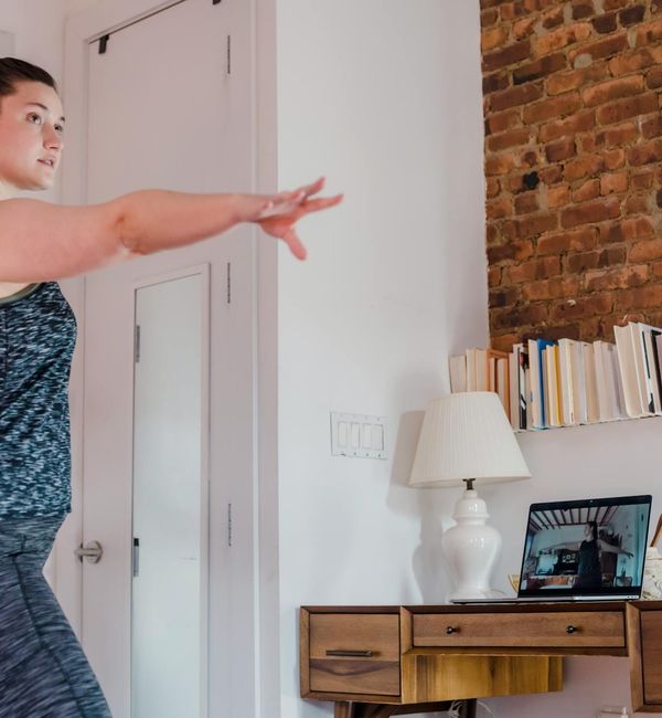 Smiling woman stretching gently on a yoga mat in a bright, modern room.